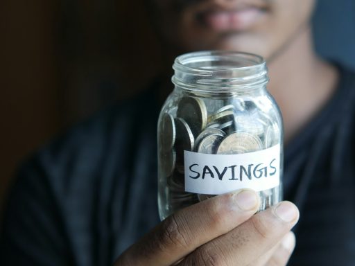 a man holding a jar with a savings label on it